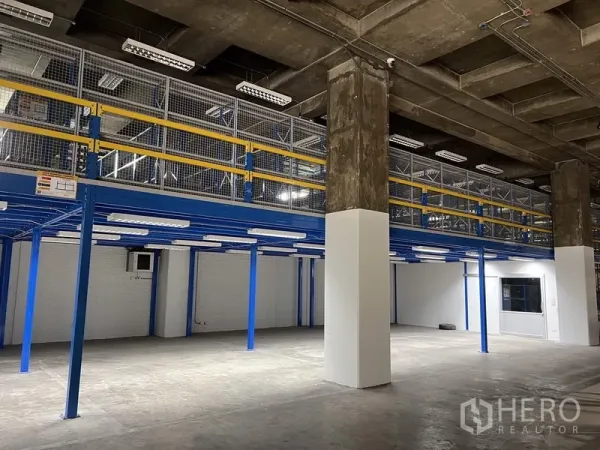 Warehouse for rent in Chatuchak, Bangkok - Clean warehouse floor with mezzanine walkway, bright lighting, and a partial office window in Chatuchak, Bangkok.