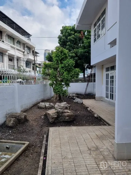 บ้าน ให้เช่าหรือขายในSathon, Bangkok - ลานข้างบ้านปูกระเบื้อง ต้นไม้ใหญ่ และกำแพงสีขาว