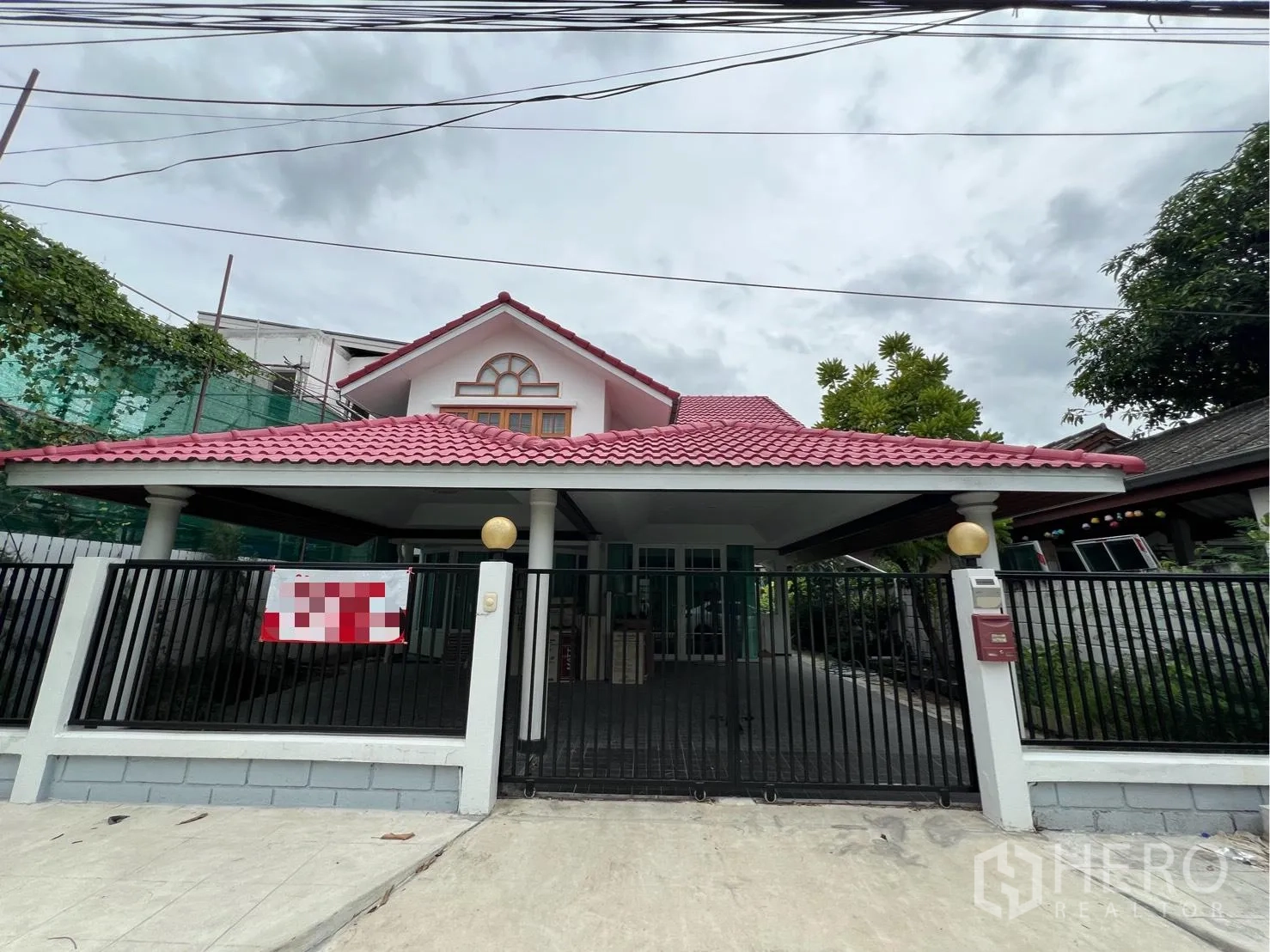 Detached House for rent in Saphan Sung, Bangkok - Front exterior of a detached house with pink tiled roof, gated driveway and covered carport.