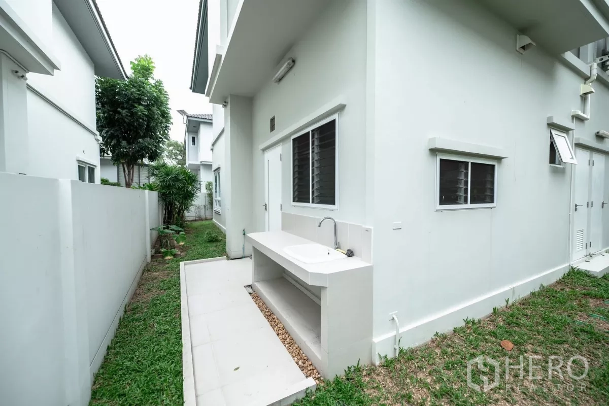 Detached House for rent or sale in Prawet, Bangkok - Side yard with outdoor sink and tiled countertop beside the house.
