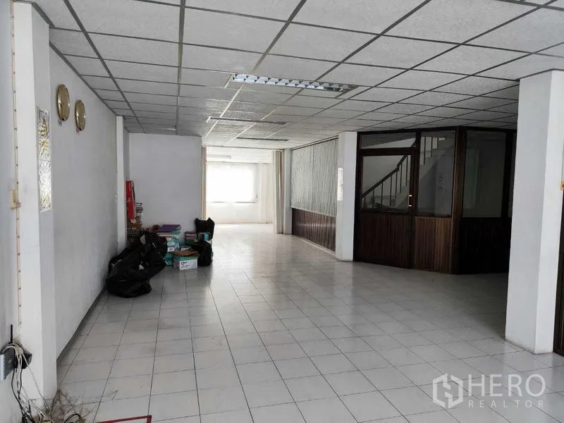 Shophouse for sale in Pathum Thani - Spacious tiled ground floor with office partition and stair access.