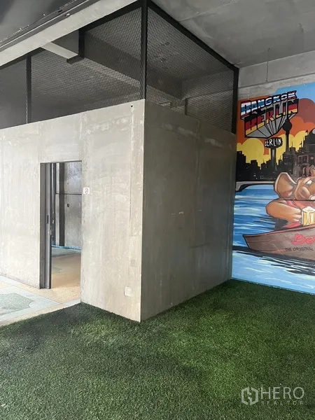 零售空间 出租在Watthana, Bangkok - 带金属网顶的混凝土服务间，旁边是河景主题壁画与草坪