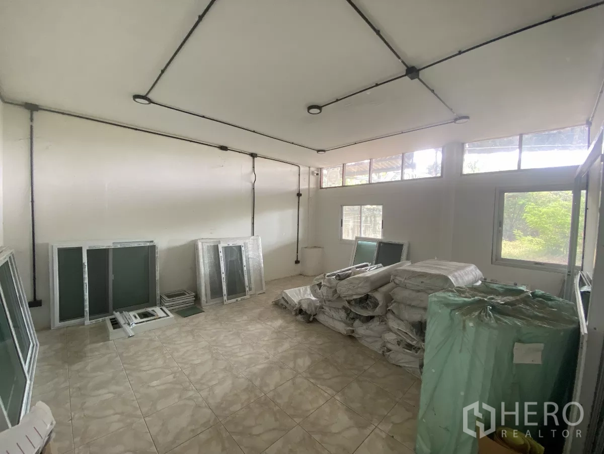 工厂 出租在Mueang Nakhon Pathom, Nakhon Pathom - 带多扇窗的杂物间，瓷砖地面，堆放包装材料。