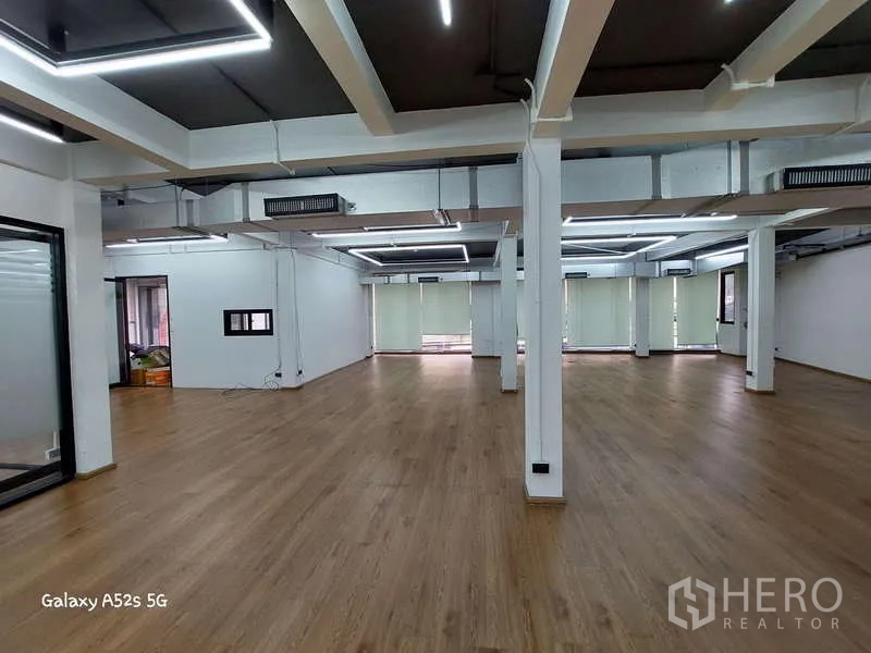 สำนักงาน ให้เช่าในKhlong Toei, Bangkok - พื้นที่ทำงานโล่งกว้าง มีเสา พื้นไม้ และมู่ลี่บังแสงริมหน้าต่าง.