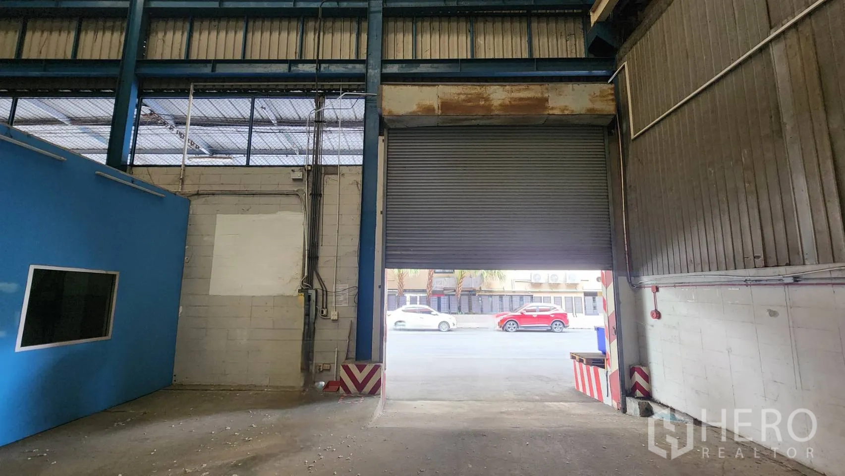 คลังสินค้า ให้เช่าในMueang Samut Prakan, Samut Prakan - ประตูม้วนโหลดสินค้า เปิดบางส่วน มองออกสู่ทางเข้าออกจากโกดัง