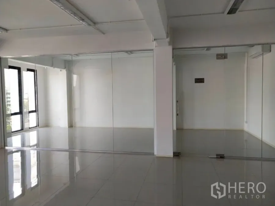 Office Space for rent in Bang Na, Bangkok - Empty office with glass-partitioned rooms and glossy tile floors.