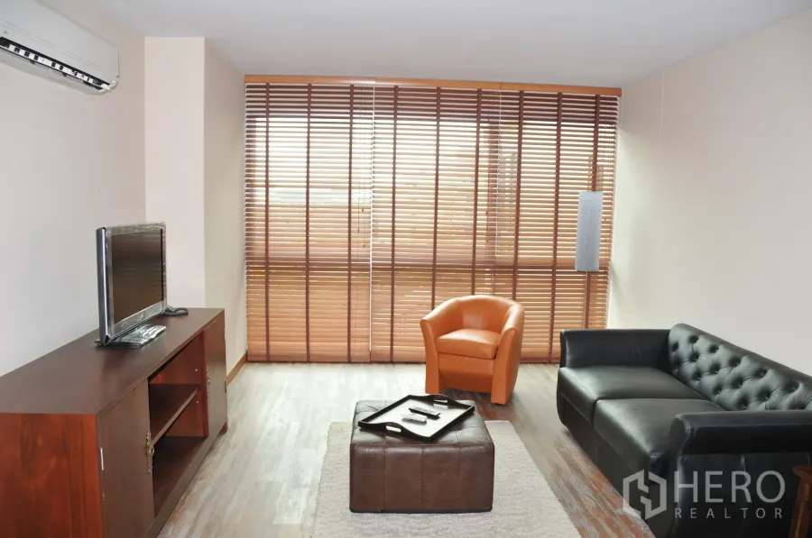 公寓 出租在Khlong Toei, Bangkok - 客厅一角，电视柜、空调与落地窗百叶。