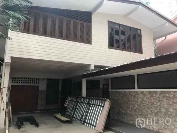 Detached House for rent in Watthana, Bangkok - Two-storey detached house exterior with covered carport, wood shutters and stone accents.