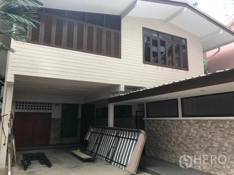 Detached House for rent in Watthana, Bangkok - Two-storey detached house exterior with covered carport, wood shutters and stone accents.