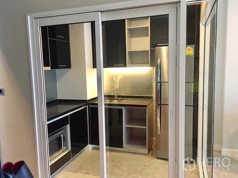 คอนโด ให้เช่าในKhlong Toei, Bangkok - ครัวปิดหลังบานเลื่อน ตู้สีดำ ตู้เย็น อ่างล้างจาน และไมโครเวฟบิวท์อิน