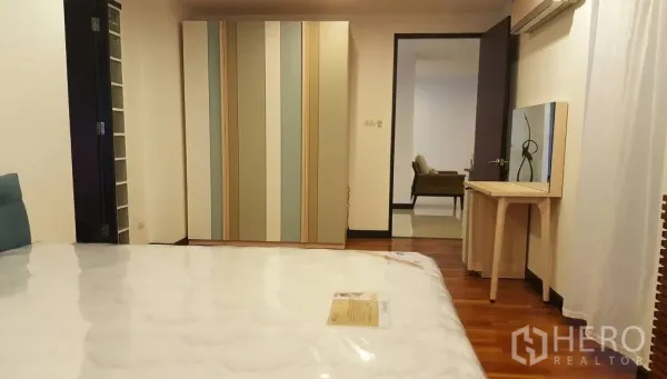 Condominium for rent in Watthana, Bangkok - Bedroom with wood floors, striped wardrobe, vanity table, and air-conditioning.