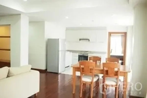 Condominium for rent in Pathum Wan, Bangkok - Dining space beside a white fitted kitchen with fridge and ceiling spotlights.