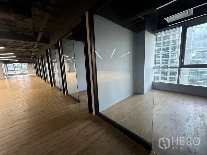 Office Space for rent in Bang Rak, Bangkok - Row of glass offices along corridor with floor-to-ceiling windows and skyline views.