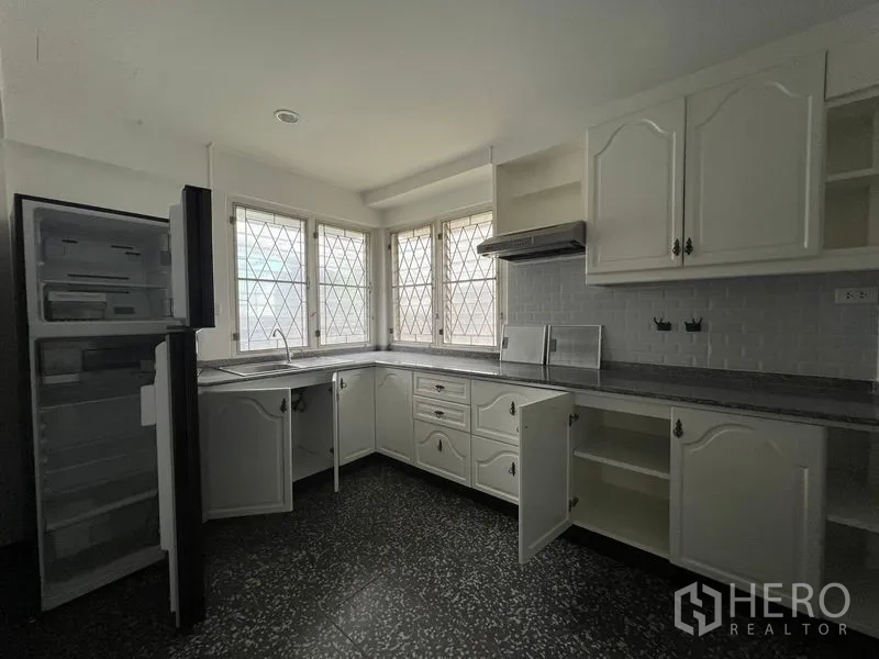 Detached House for rent in Saphan Sung, Bangkok - Corner kitchen with white cabinets, stone countertops and lattice windows.