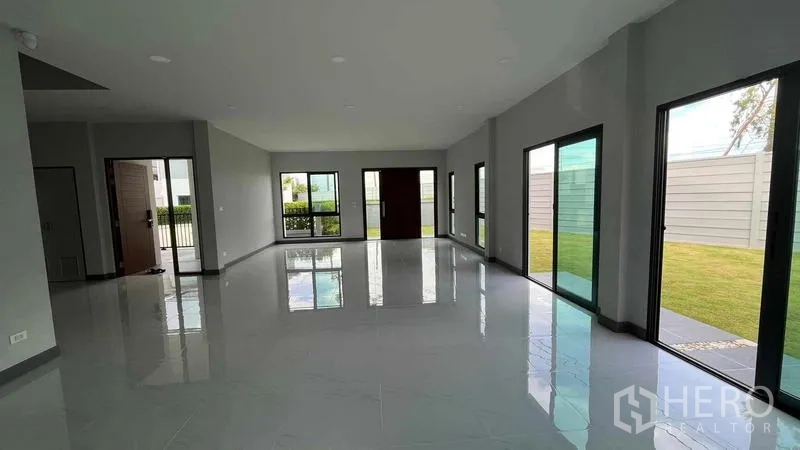 Detached House for sale in Bang Phli, Samut Prakan - Sunlit open-plan room with numerous windows and views of the fenced yard.
