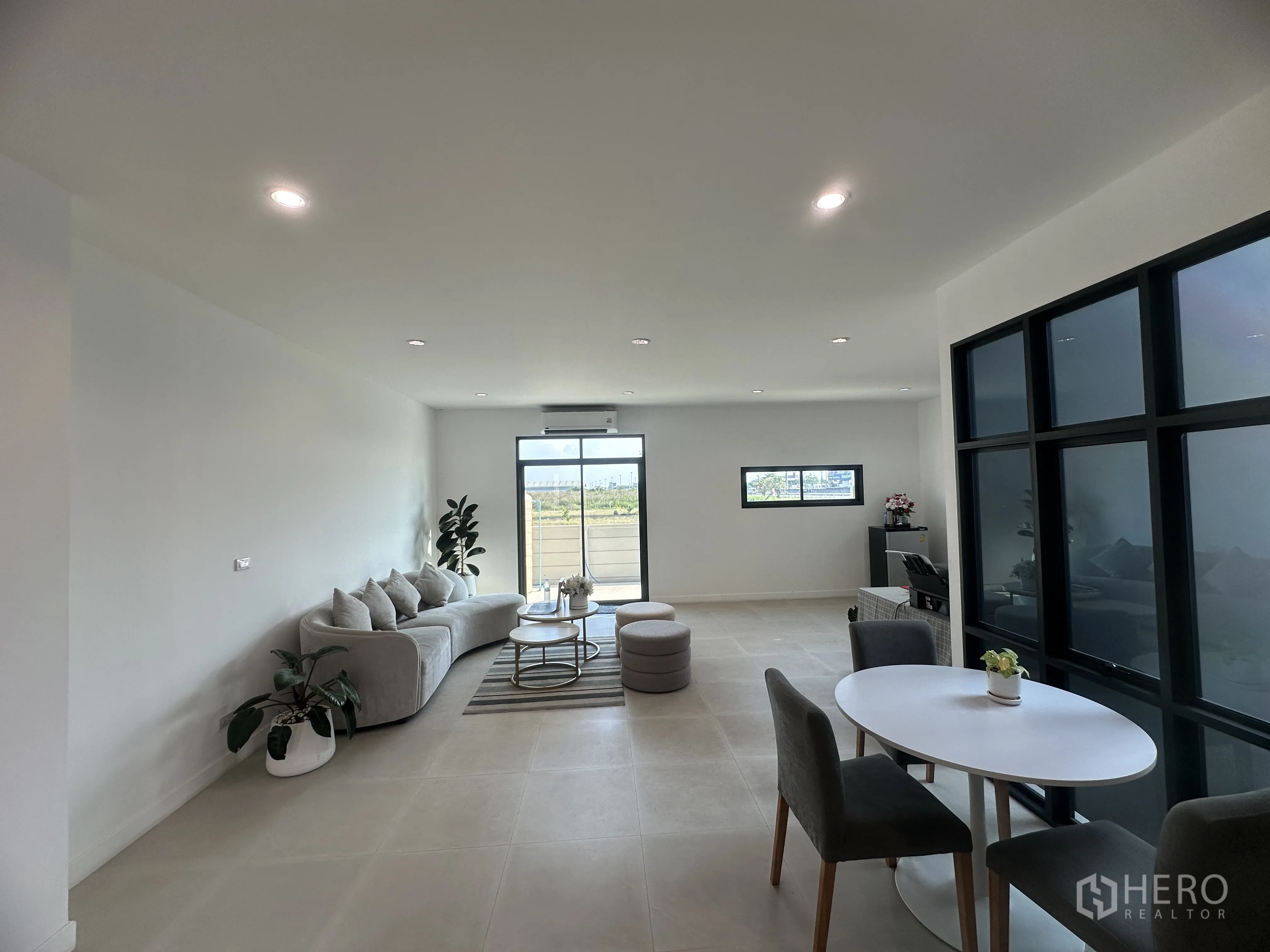 Home Office for sale in Khlong Luang, Pathum Thani - Staged lounge and dining zone with sofa set, round table, and sliding door to the terrace.