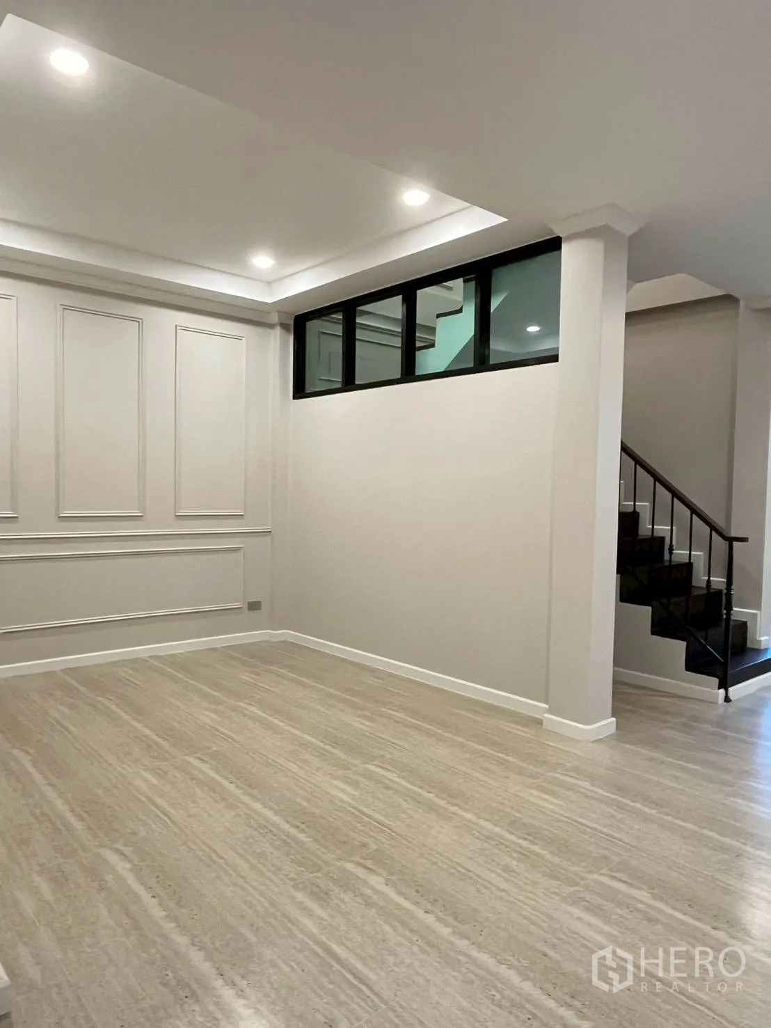ทาวน์เฮาส์ for rent in Khlong Toei, Bangkok - พื้นที่นั่งเล่นโปร่งไฟดาวน์ไลต์ ผนังบัวปูน พื้นลายไม้ และช่องหน้าต่างใกล้บันได.