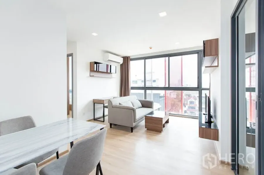 Condominium for rent in Watthana, Bangkok - Open-plan living and dining area with large windows and abundant natural light.