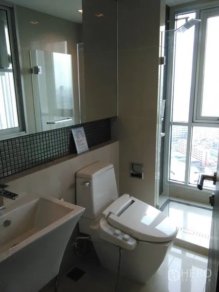Condominium for rent or sale in Sathon, Bangkok - Contemporary bathroom with glass shower, smart toilet and a window for natural light.