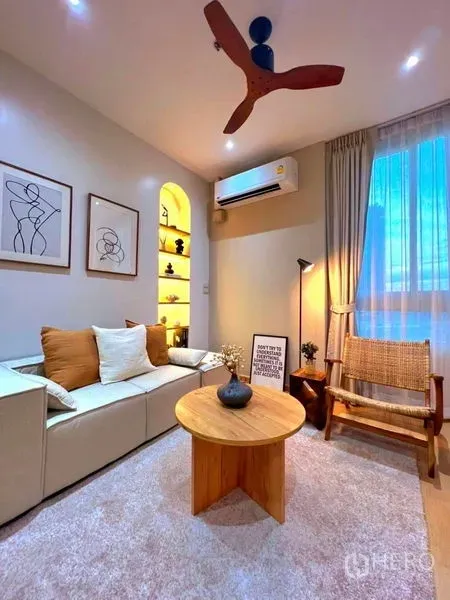 Condominium for rent in Ratchathewi, Bangkok - Stylish lounge with sofa, arched display niche, ceiling fan and large window near BTS.