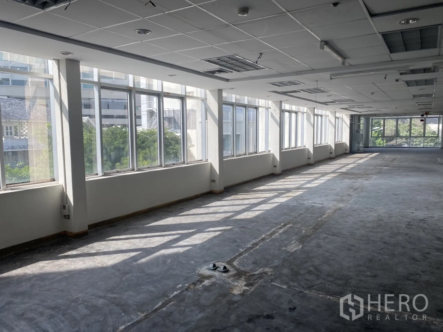 Office Space for rent in Khlong Toei, Bangkok - Long row of tall windows brightening an empty office space with unfinished flooring.