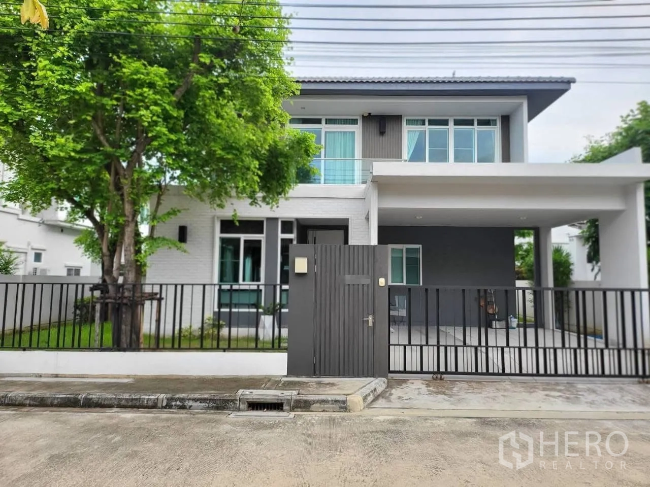 บ้านเดี่ยว for rent in Bang Phli, Samut Prakan - ด้านหน้าบ้านสองชั้นพร้อมรั้ว ประตู และที่จอดรถในร่ม