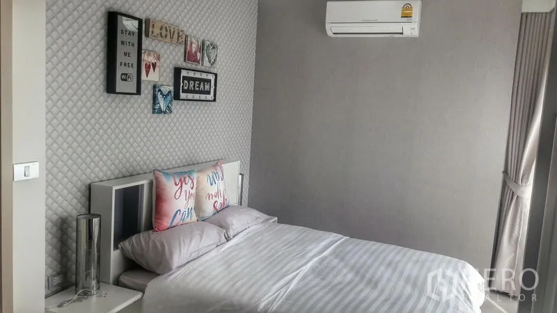 Condominium for rent in Khlong Toei, Bangkok - Bright bedroom with double bed, feature wall, and air conditioner