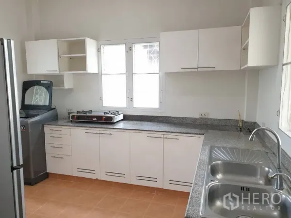 Detached House for rent in Khlong Toei, Bangkok - Fitted kitchen with white cabinets, granite countertops, double sink, fridge, washer and gas cooktop.