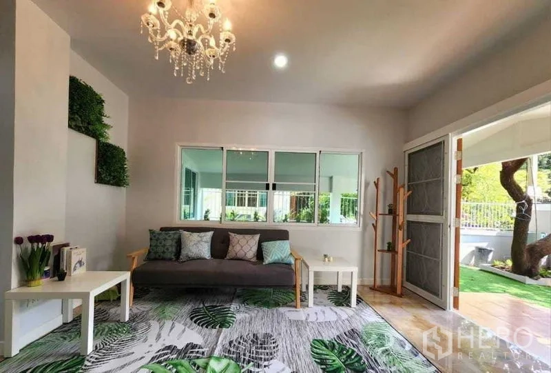 บ้าน ให้เช่าในLam Luk Ka, Pathum Thani - ห้องนั่งเล่นสว่าง โคมระย้า โซฟา และหน้าต่างบานเลื่อนมองสู่สวน