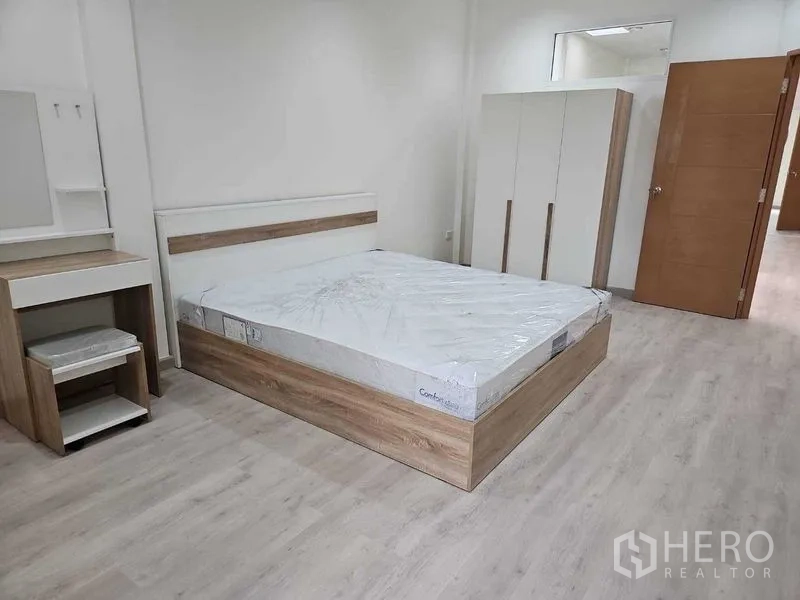 Townhouse for rent in Khlong Toei, Bangkok - Bright bedroom with light wood flooring, queen bed, wardrobe and dressing table.