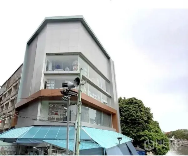 Shophouse for rent in Pathum Wan, Bangkok - Angled exterior view of a multi-storey shophouse showcasing large display windows and clean lines.
