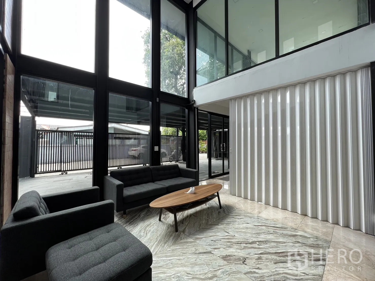 บ้าน ให้เช่าหรือขายในPhra Khanong, Bangkok - ห้องนั่งเล่นพร้อมชั้นลอยและฉากกั้นแบบพับสีขาวข้างผนังกระจก