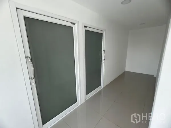 零售空间 出租在Huai Khwang, Bangkok - 现代商铺走廊，一侧有两扇磨砂玻璃门与亮面地砖。