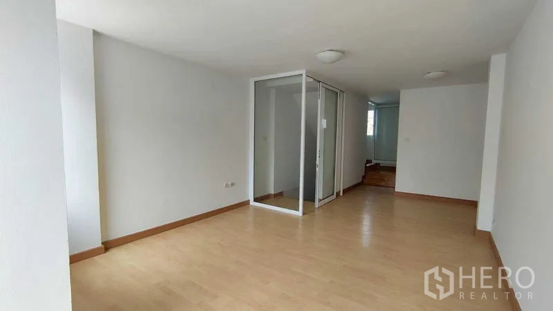 Townhouse for sale in Bang Khen, Bangkok - Spacious living area with laminate floors and a glass-enclosed multipurpose room.