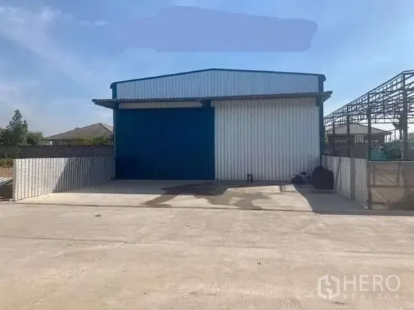 货栈 出租在Khlong Sam Wa, Bangkok - 蓝白配色仓库正立面，前方大面积硬质场地与围栏入口。