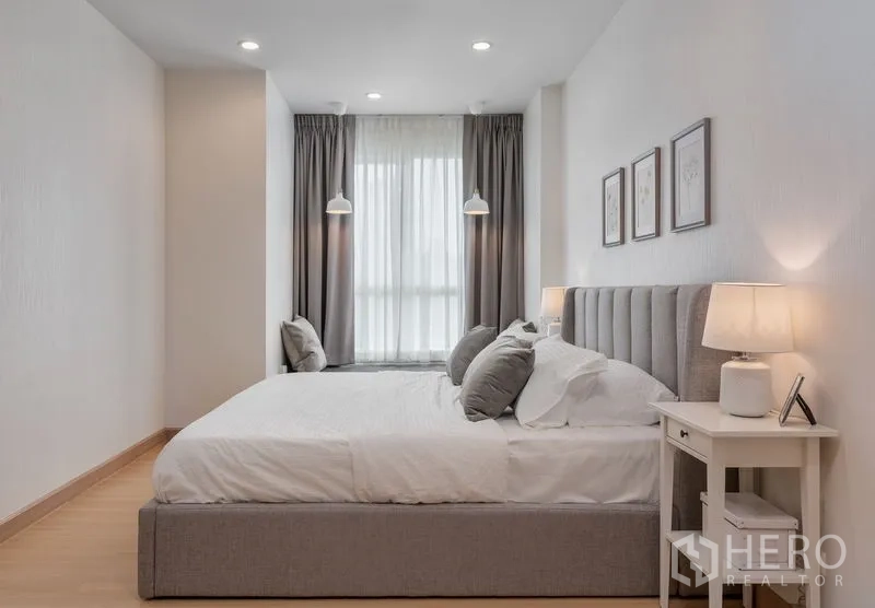 Condominium for sale in Yan Nawa, Bangkok - Spacious bedroom featuring a king bed, window seat nook and soft grey blackout curtains.