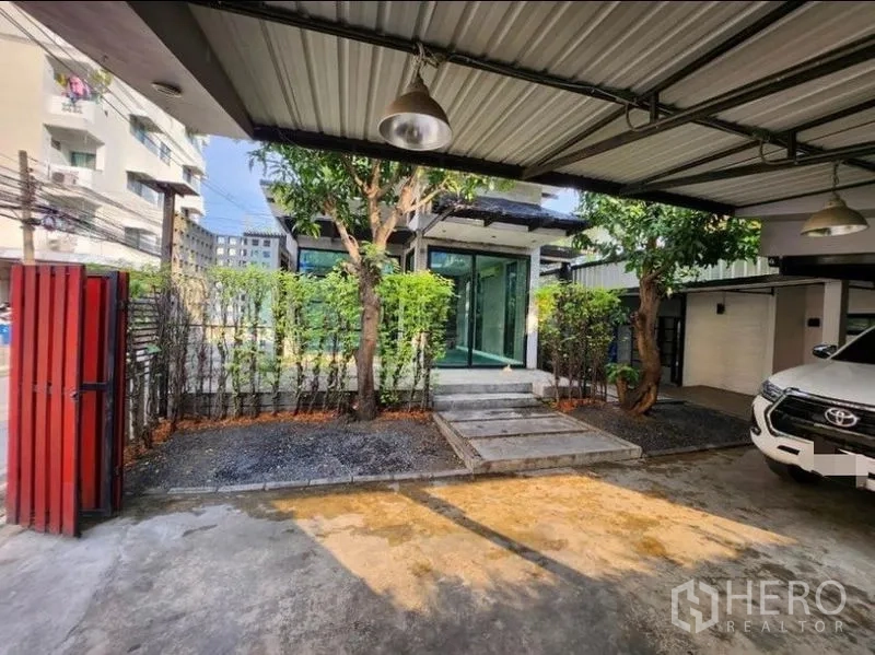 带办公室的家 出租在Lat Phrao, Bangkok - 金属顶车棚，可停多辆车，绿篱与大门通往室内。