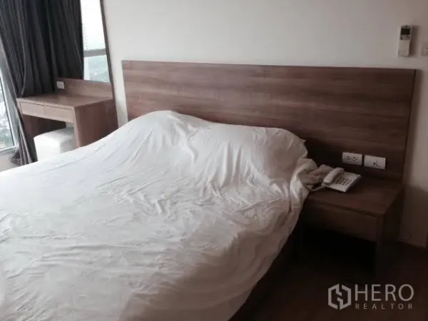 คอนโด ให้เช่าในKhlong Toei, Bangkok - ห้องนอนหลักหัวเตียงไม้ โต๊ะข้างเตียง โต๊ะทำงานริมหน้าต่าง โทนสีเรียบ