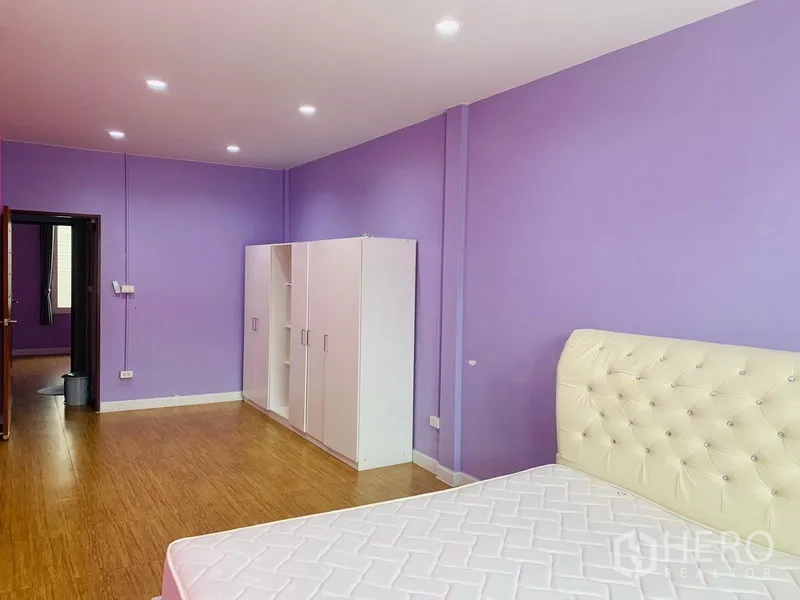 Detached House for sale in Din Daeng, Bangkok - Large bedroom with purple walls, wood flooring and an upholstered headboard.