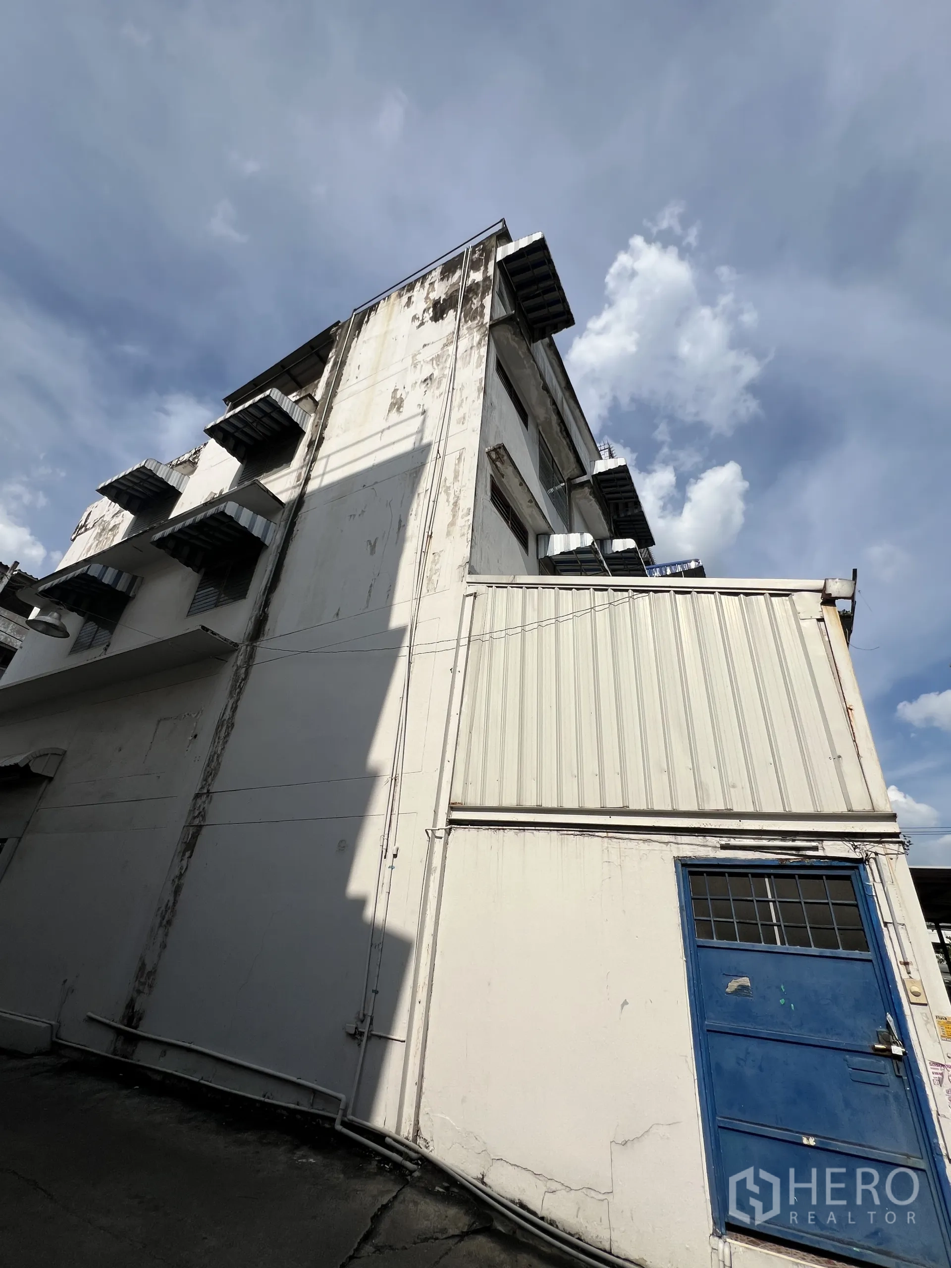 零售空间 出租在Suan Luang, Bangkok - 白色商业楼侧立面，高挑，金属构件明显。