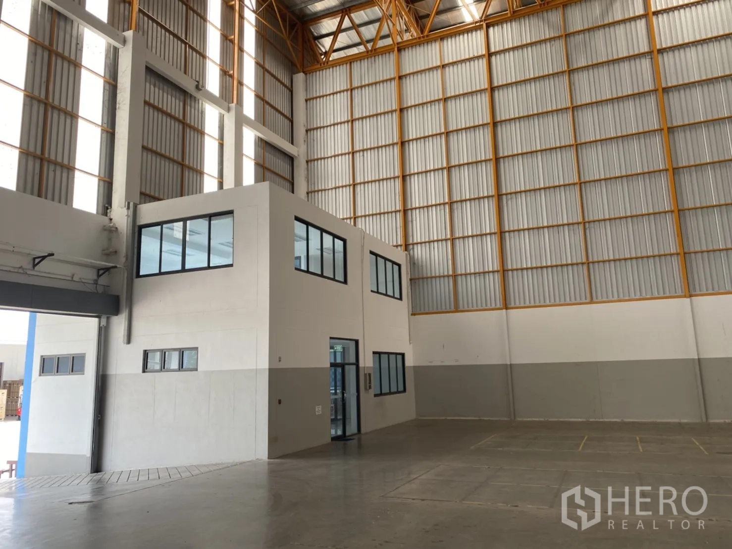 Warehouse for rent in Chachoengsao - High bay warehouse zone with mezzanine office cube and wide concrete floor.