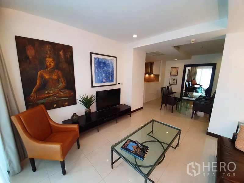 คอนโด ให้เช่าในWatthana, Bangkok - มุมนั่งเล่นมีชั้นวางทีวี เก้าอี้สีส้ม และภาพศิลปะขนาดใหญ่