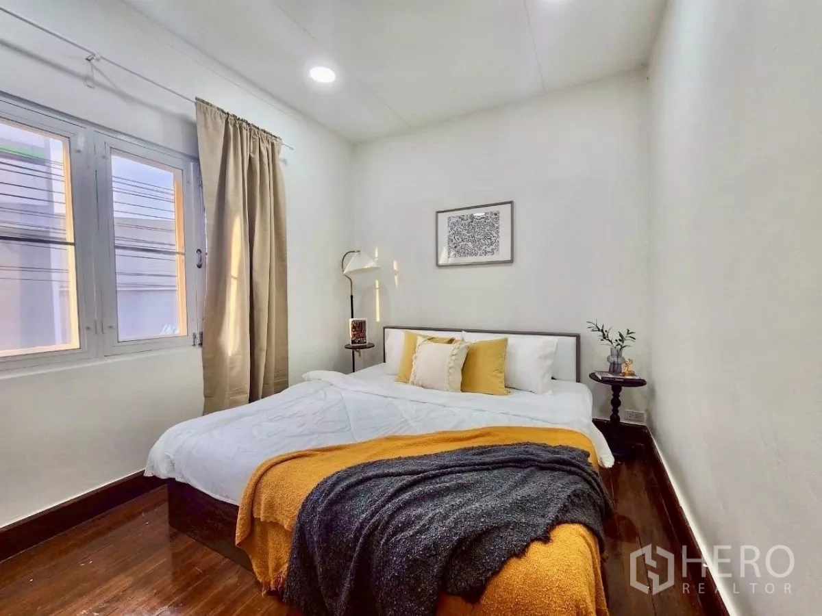 Detached House for rent in Chatuchak, Bangkok - Corner bedroom with large windows, bedside tables and warm wooden floor.