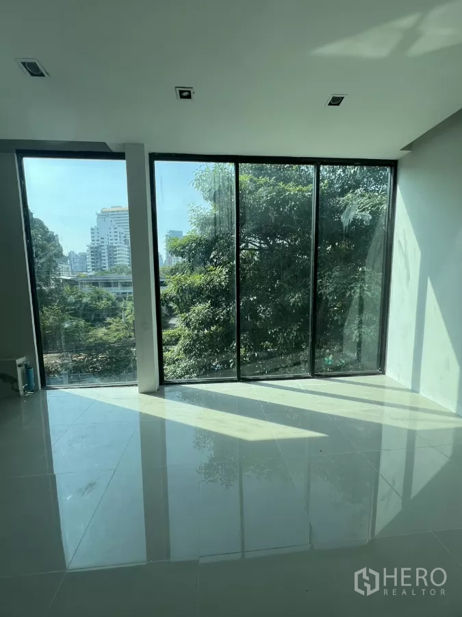 零售空间 出租在Watthana, Bangkok - 采光充足的转角空间，落地全景窗与亮面地砖，面向茂密绿树。