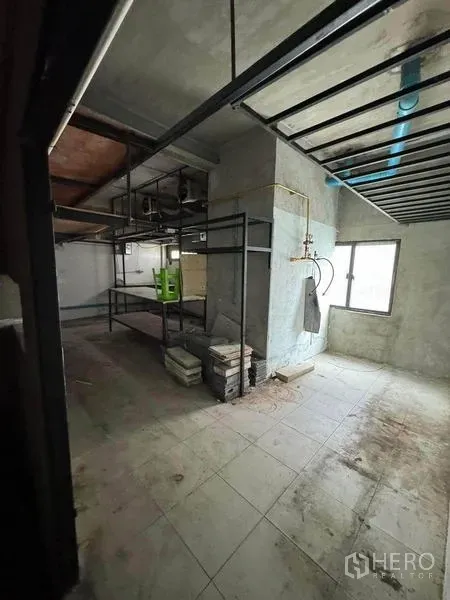 店屋 出租在Phaya Thai, Bangkok - 未完工的后场房间，混凝土墙面、窗户、外露管线与金属货架。