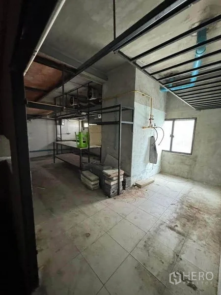 店屋 出租在Phaya Thai, Bangkok - 未完工的后场房间，混凝土墙面、窗户、外露管线与金属货架。