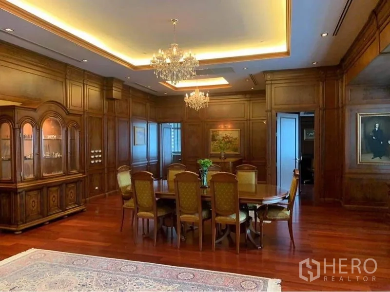 Condominium for rent in Watthana, Bangkok - Formal dining area with crystal chandeliers, display cabinet, and an oval table with upholstered chairs on hardwood floors.