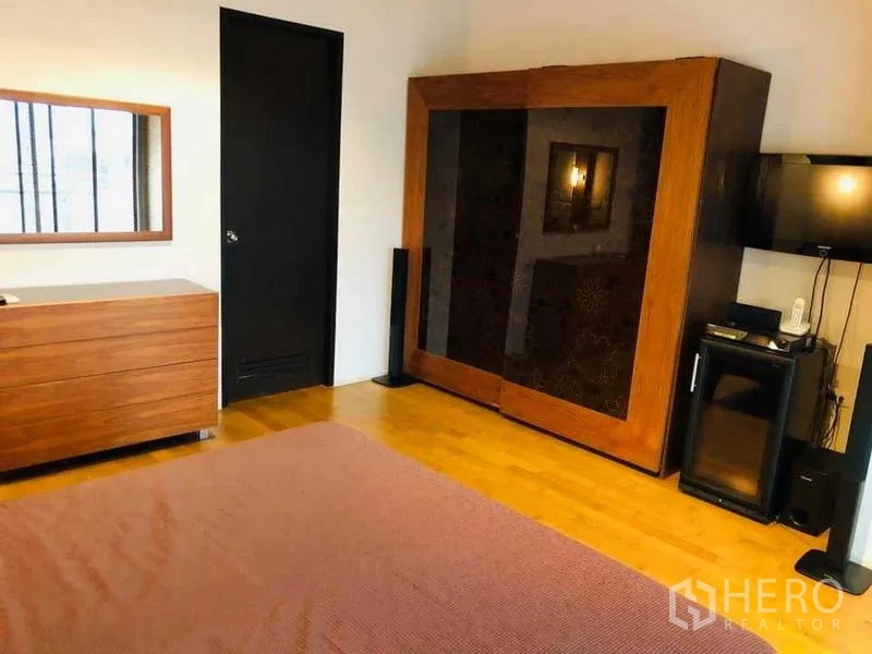 คอนโด ให้เช่าหรือขายในWatthana, Bangkok - มุมมองห้องนอนอีกด้าน แสดงตู้เสื้อผ้า ทีวี และตู้เย็นเล็กบนพื้นไม้