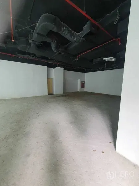 零售空间 出租在Bang Rak, Bangkok - 宽敞毛坯店铺，黑色高天花与红色喷淋管道清晰可见。