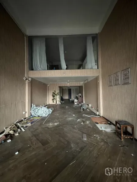 店屋 出租在Khlong Toei, Bangkok - 挑高商铺室内带夹层窗，木质条纹墙面与深色人字拼地板，待翻新。